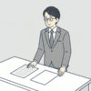机の上に紙が二枚。左は行が書かれ、右は白紙。会社員が一人、左の紙を見ている