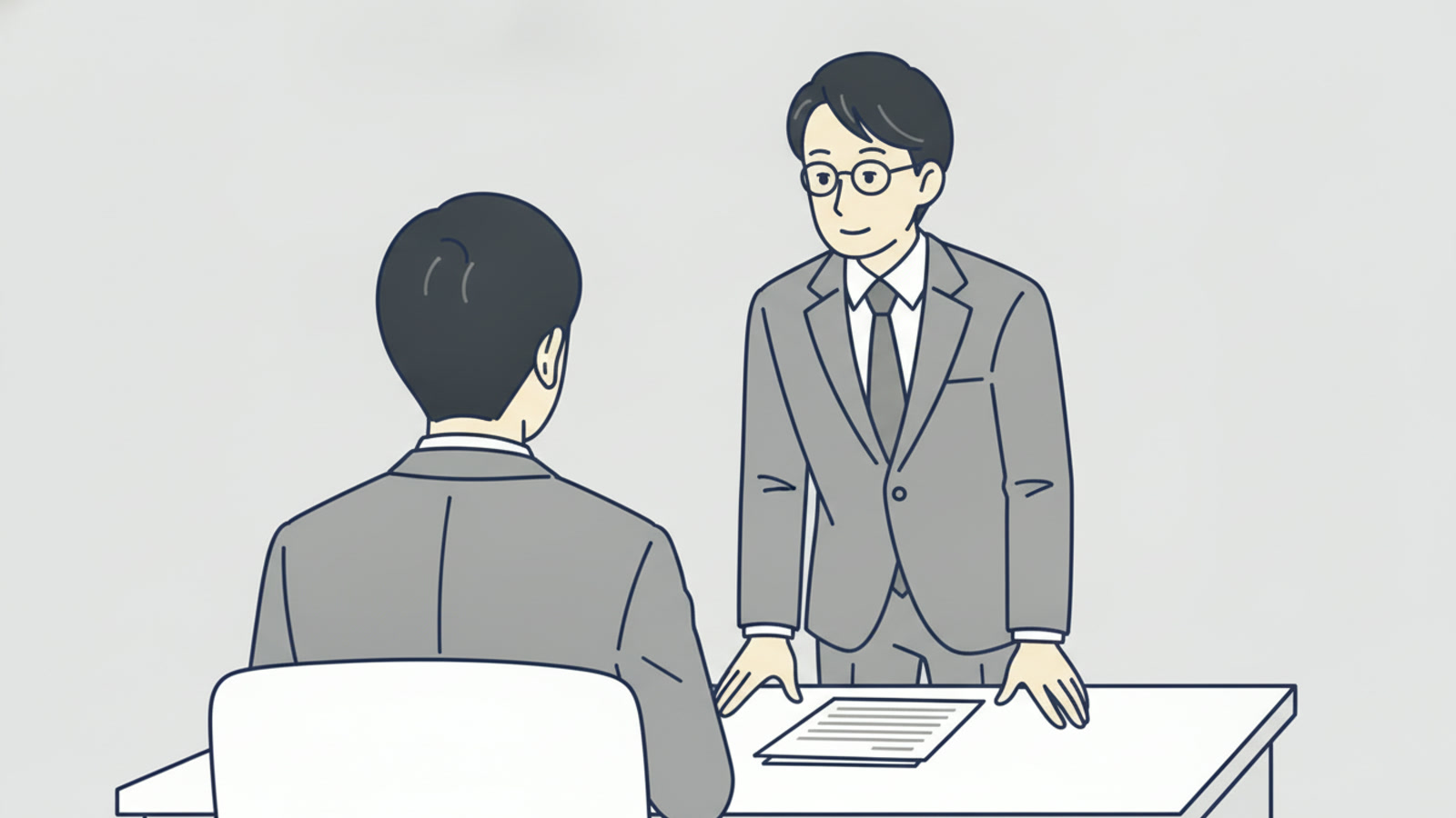 管理職が部下の席の横に立ち、穏やかに話を聞いている(部下は後ろ姿)