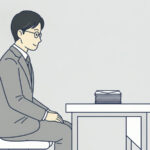 机に向かう人物の前に、届いた封筒の束が置かれている