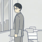 夕方のオフィスの窓際で外を見ている会社員